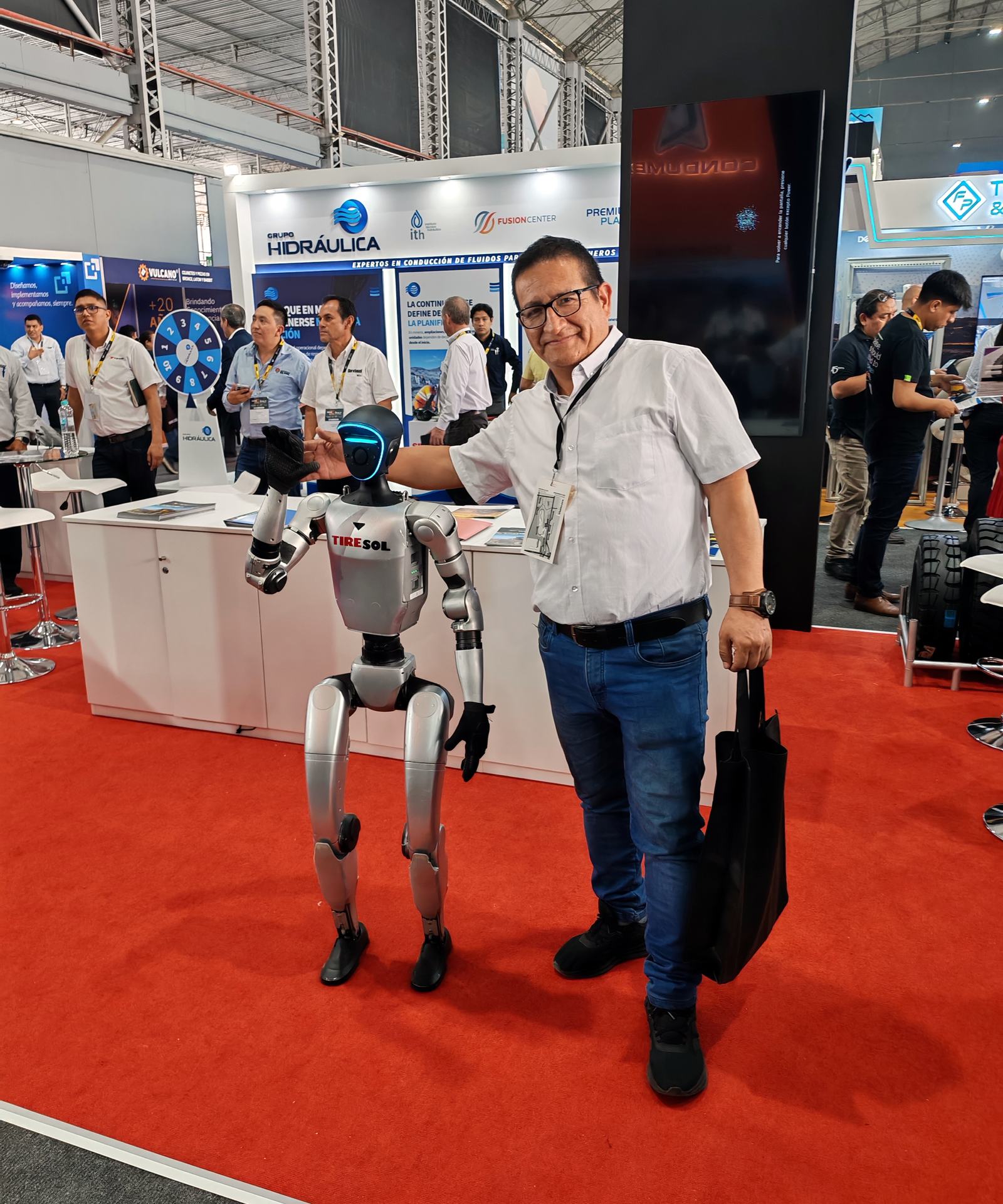 Manuel Huaripata junto a un robot humanoide en una feria de tecnología