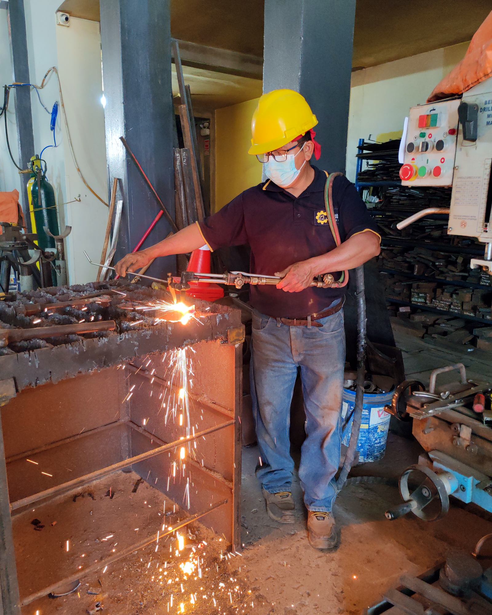 Operario con casco y equipo de protección realizando un corte de metal en planta
